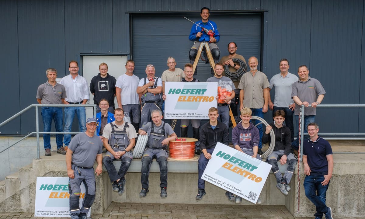 Das Team von Hoefert Elektro vor der eigenen Halle in der Neidenburger Straße in Bremen-Hemelingen, mit Kabeltrommel, Werkzeug und Firmenbannern.